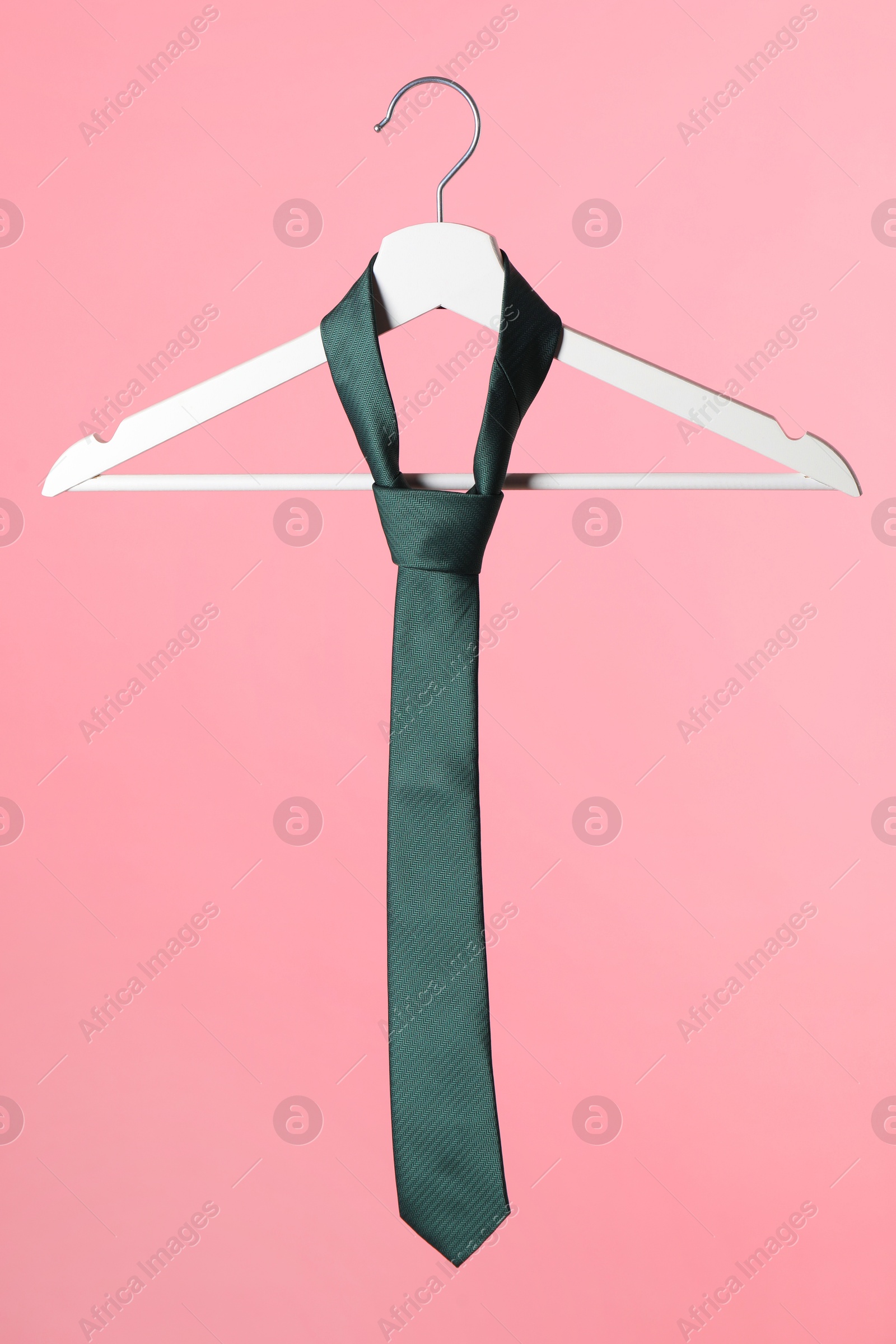 Photo of Hanger with teal tie on pink background