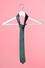 Photo of Hanger with teal tie on pink background