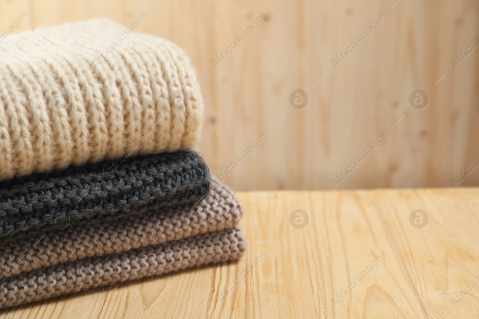 Photo of Knitted scarfs on wooden table, space for text