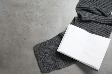 Photo of Knitted scarf and notebook on gray table, top view. Space for text