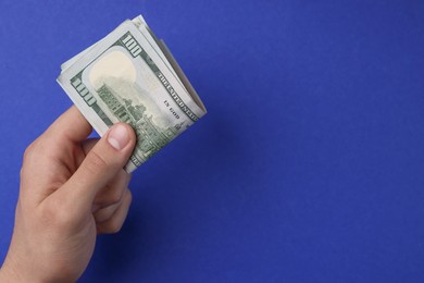 Photo of Money exchange. Man holding dollar banknotes on blue background, top view. Space for text