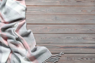 Photo of Soft checkered scarf on wooden table, top view. Space for text