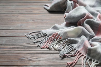 Photo of Soft checkered scarf on wooden table, closeup. Space for text