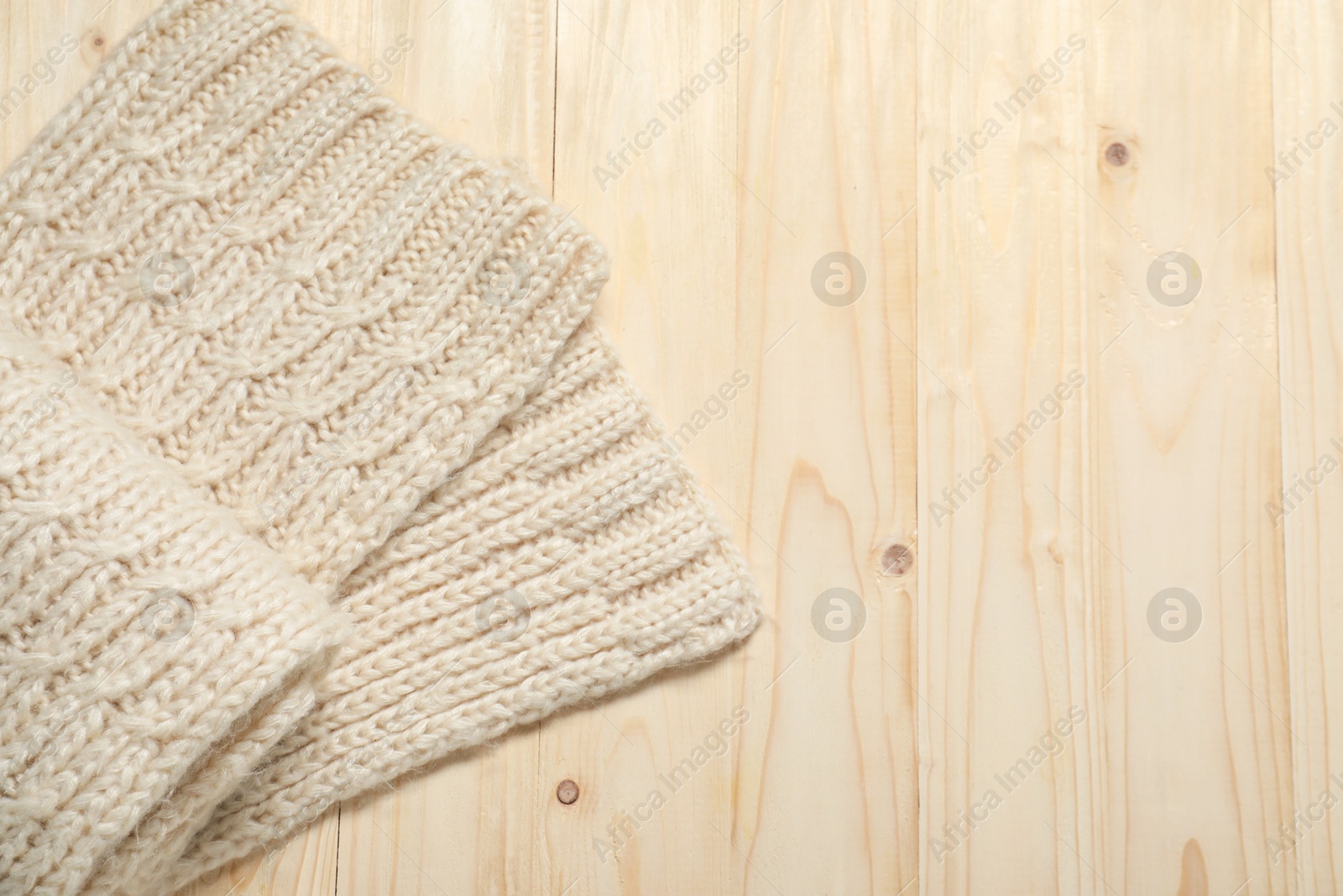 Photo of Knitted scarf on wooden table, top view. Space for text