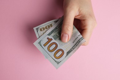 Photo of Money exchange. Woman holding dollar banknotes on pink background, top view