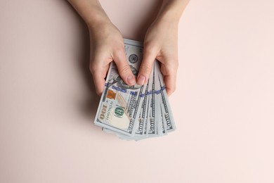 Photo of Money exchange. Woman holding dollar banknotes on beige background, top view