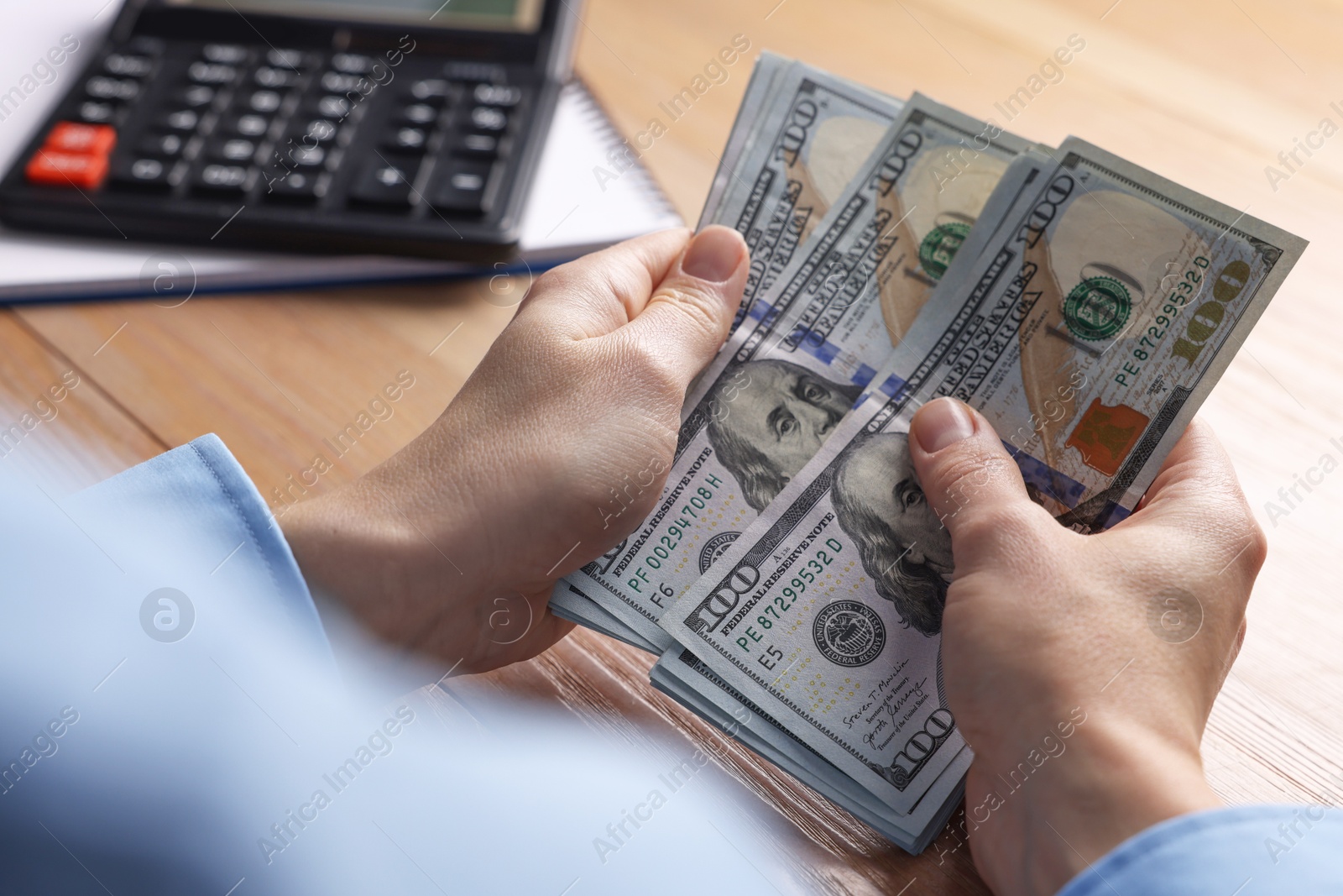 Photo of Money exchange. Woman counting dollar banknotes at wooden table, closeup