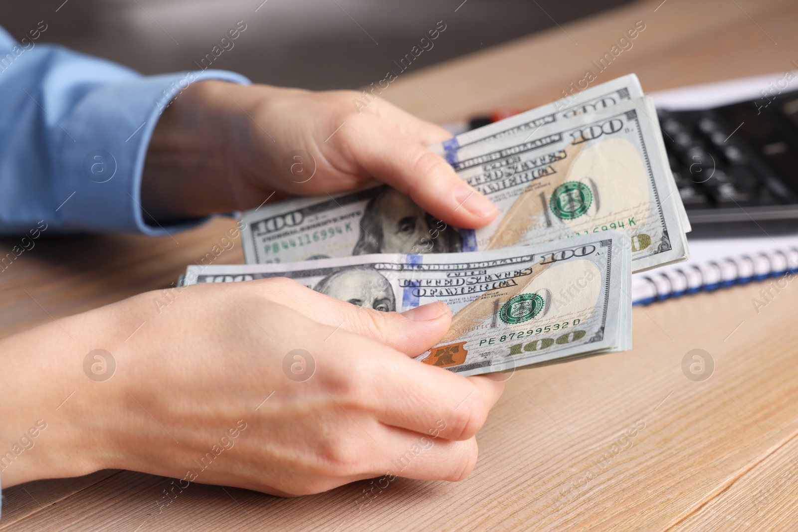 Photo of Money exchange. Woman counting dollar banknotes at wooden table, closeup