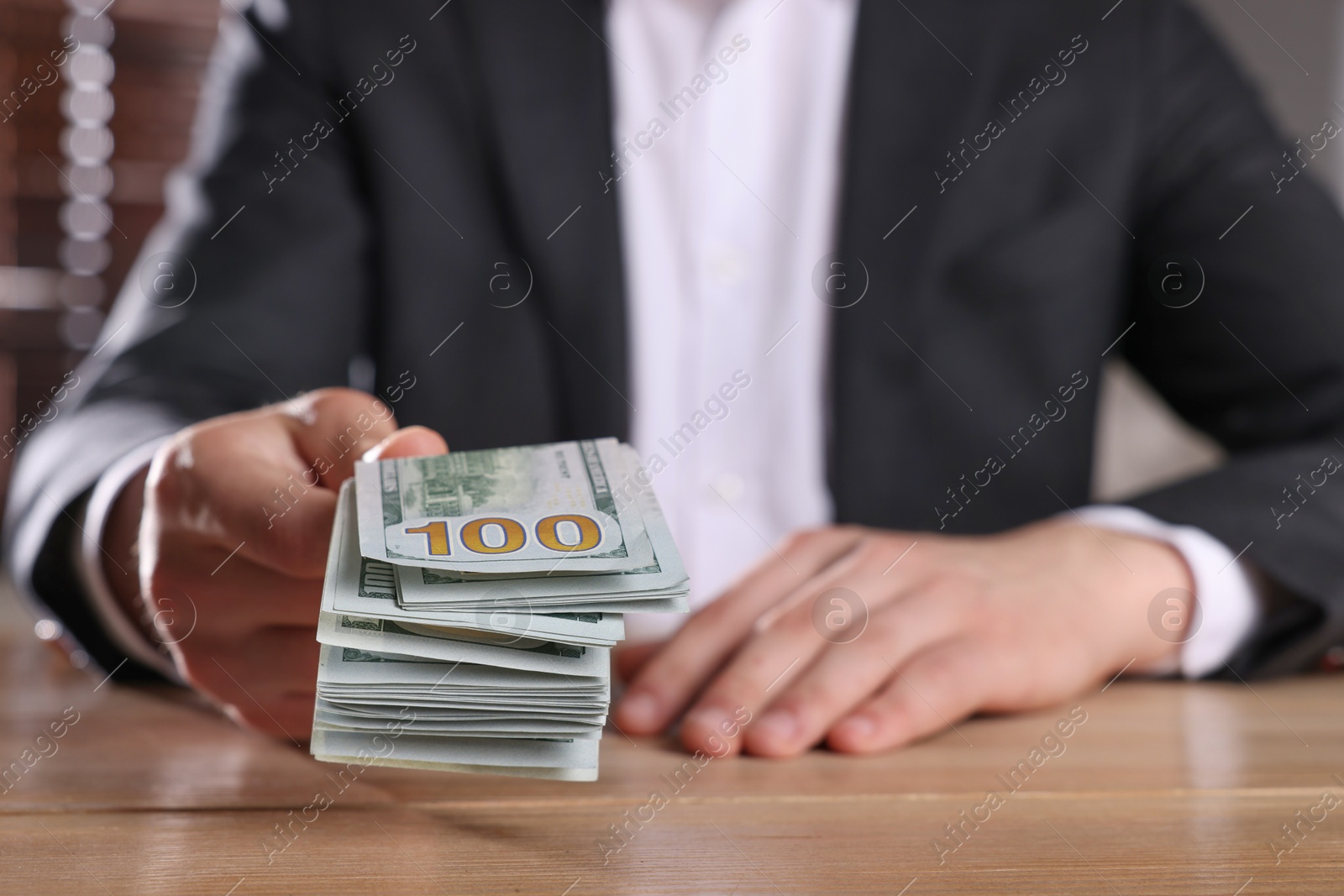 Photo of Money exchange. Man holding dollar banknotes at wooden table, closeup