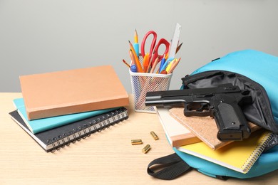 Gun, bullets and school stationery on wooden table