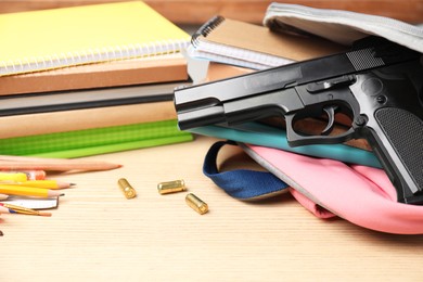 Photo of Gun, bullets and school stationery on wooden table