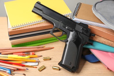 Gun, bullets and school stationery on wooden table