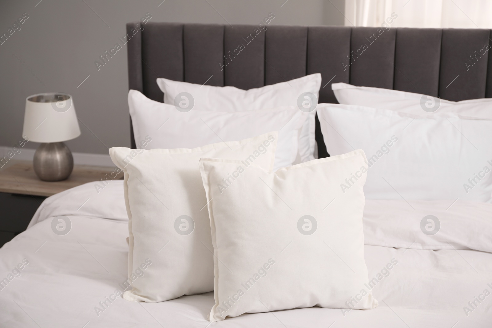 Photo of Many soft white pillows and duvet on bed indoors