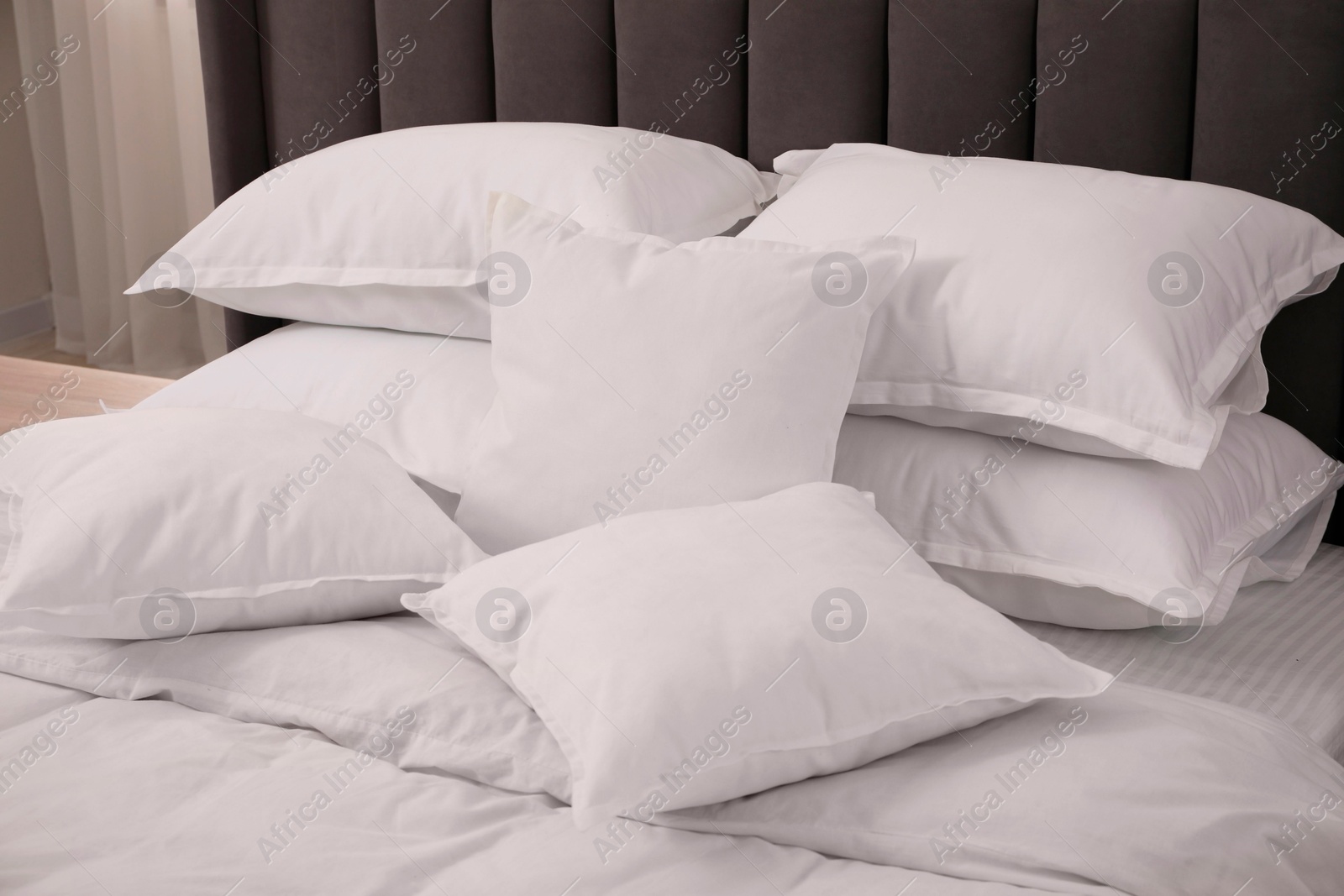 Photo of Many soft white pillows and duvet on bed indoors