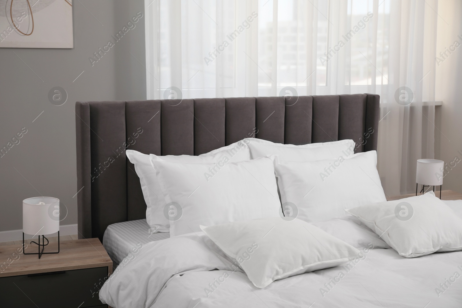 Photo of Many soft white pillows and duvet on bed indoors