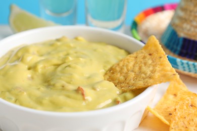 Photo of Delicious guacamole with nachos chips on table, closeup