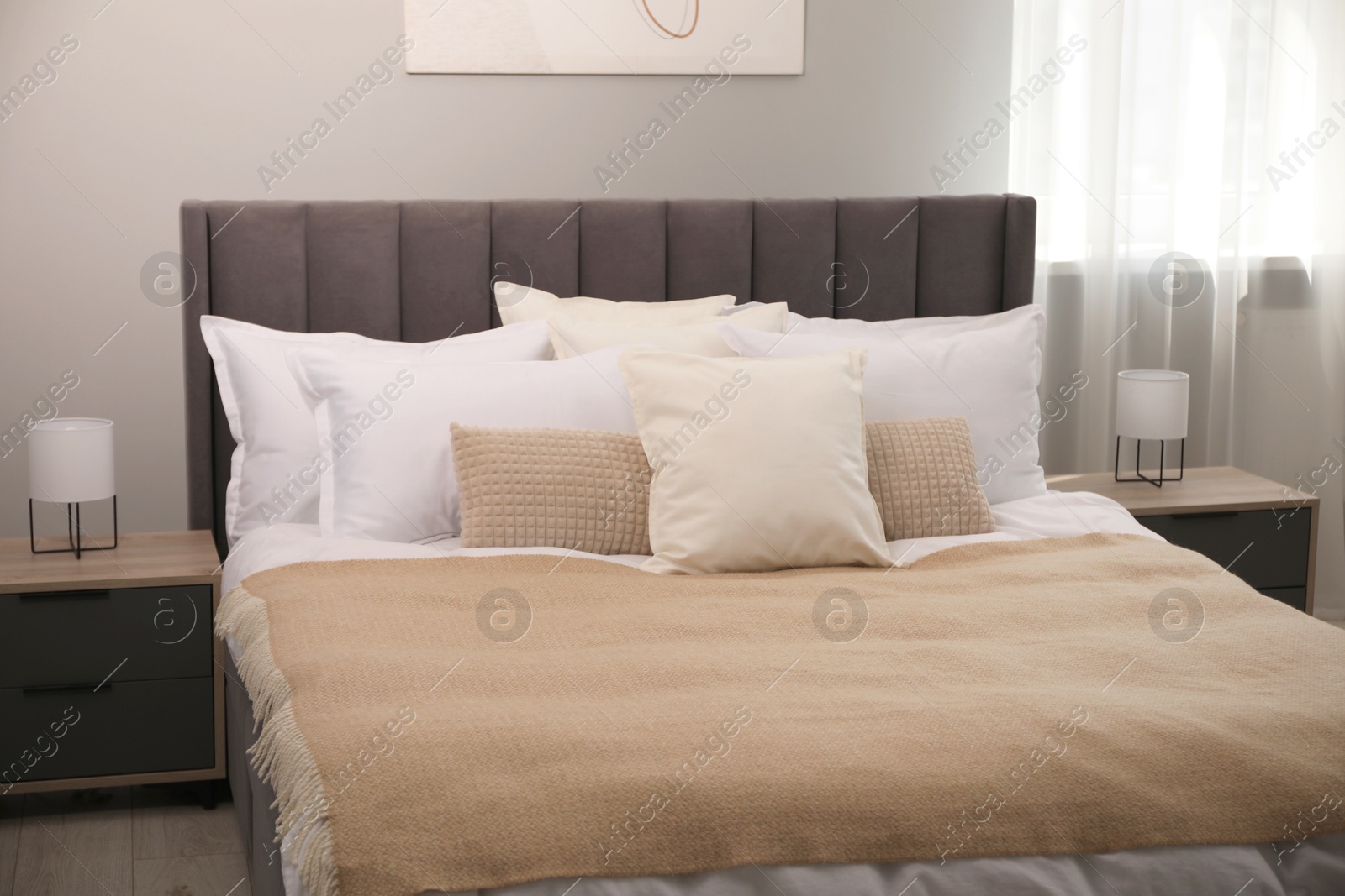 Photo of Many soft white pillows and blanket on bed indoors