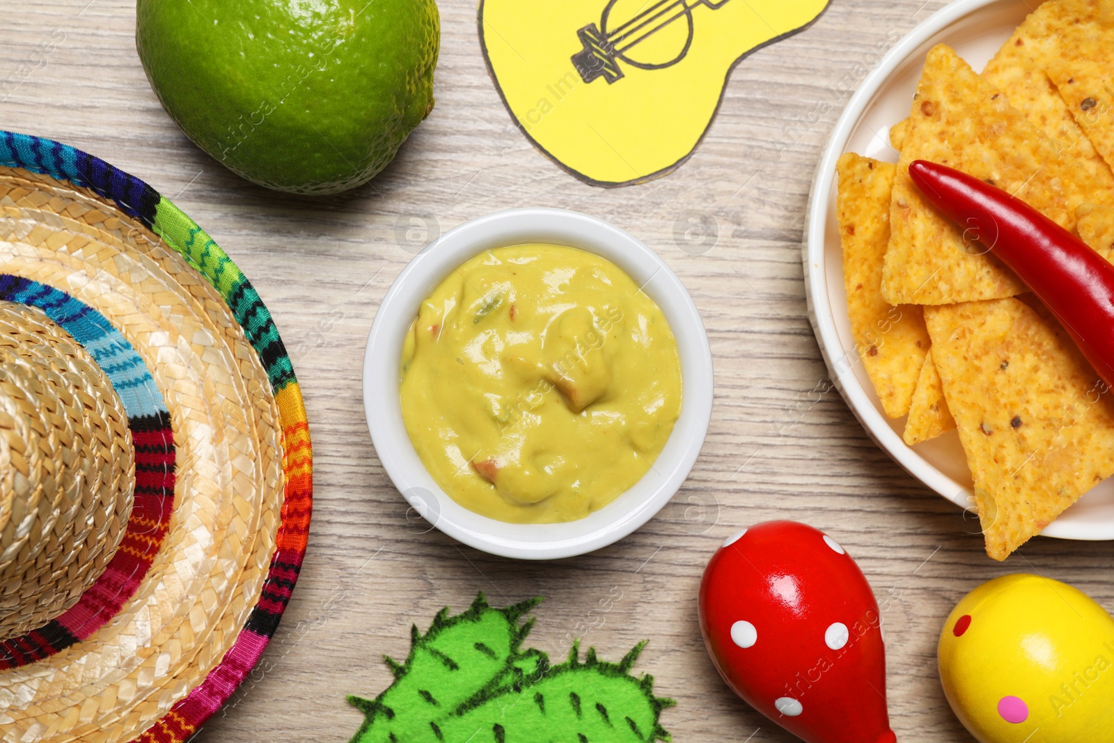 Photo of Flat lay composition with guacamole and Mexican sombrero hat on wooden table