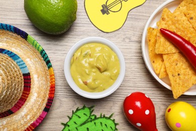 Flat lay composition with guacamole and Mexican sombrero hat on wooden table