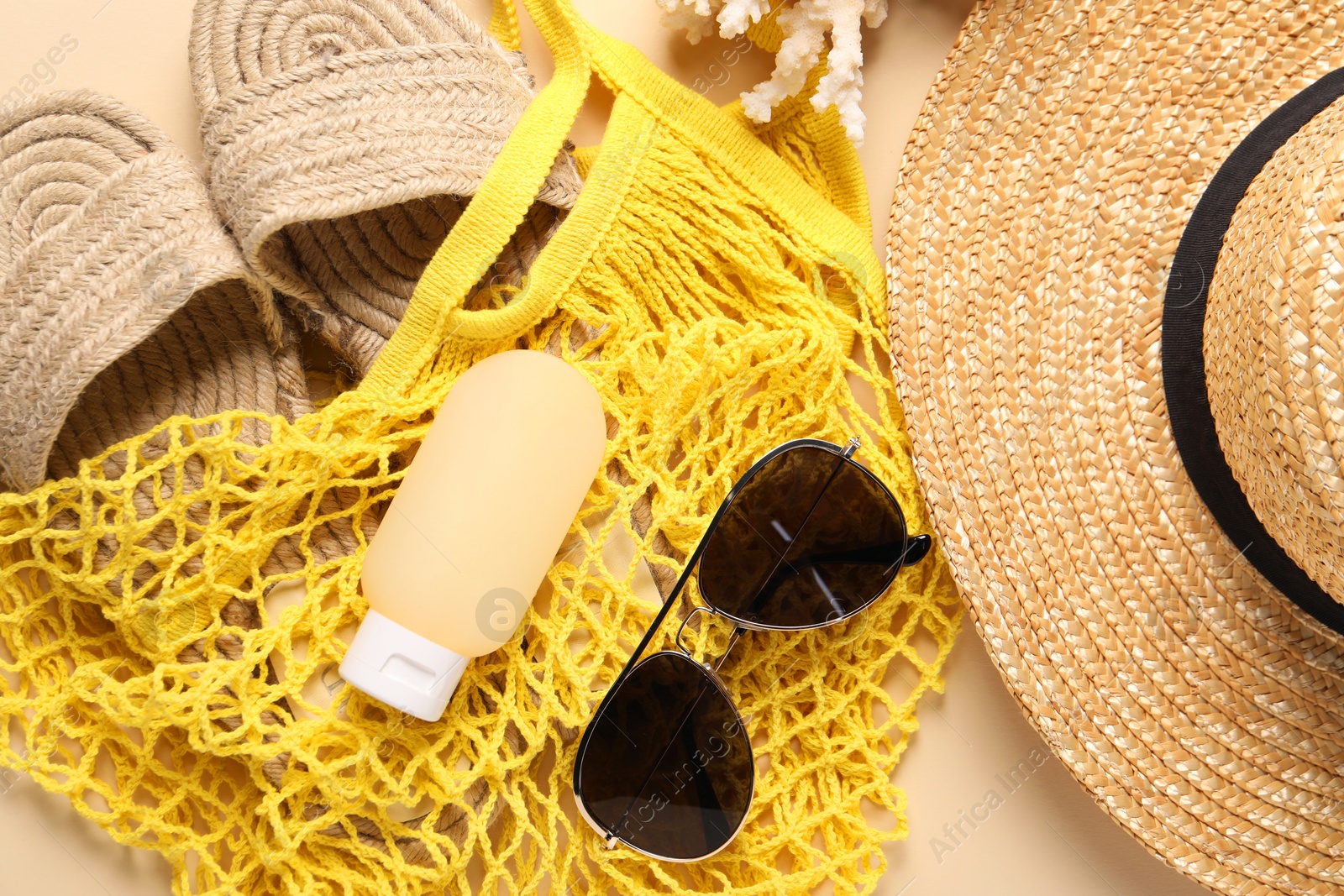 Photo of String bag and different beach accessories on beige background, top view