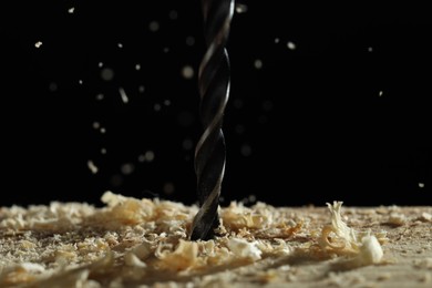 Electric drill and sawdust on black background, closeup