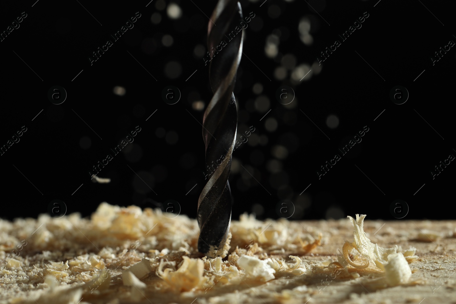 Photo of Electric drill and sawdust on black background, closeup