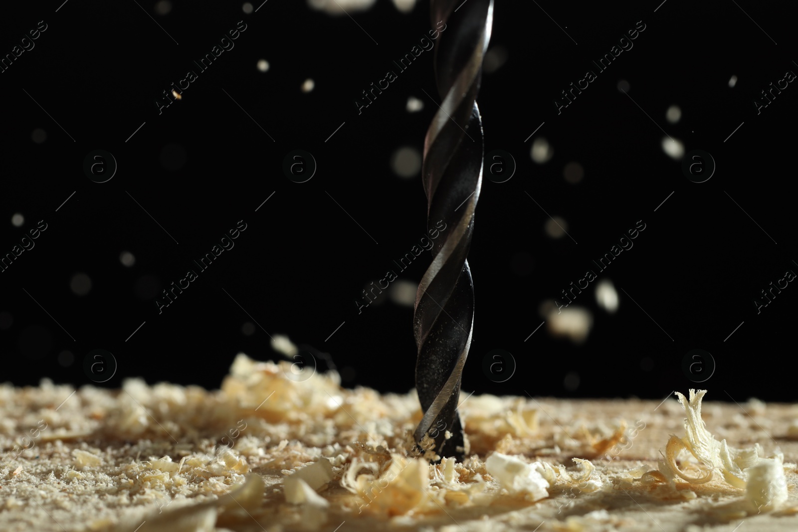 Photo of Electric drill and sawdust on black background, closeup