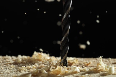 Photo of Electric drill and sawdust on black background, closeup