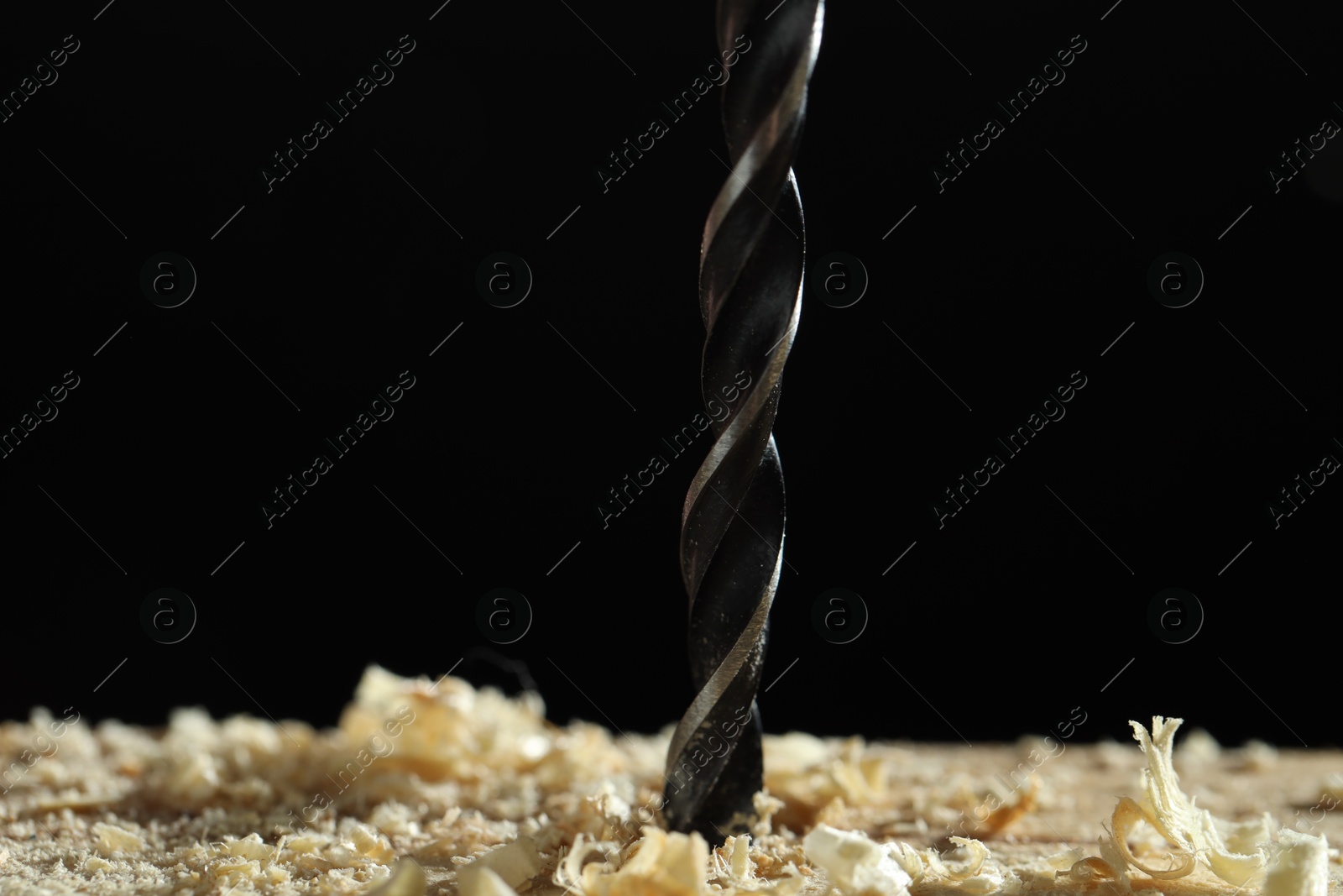 Photo of Electric drill and sawdust on black background, closeup