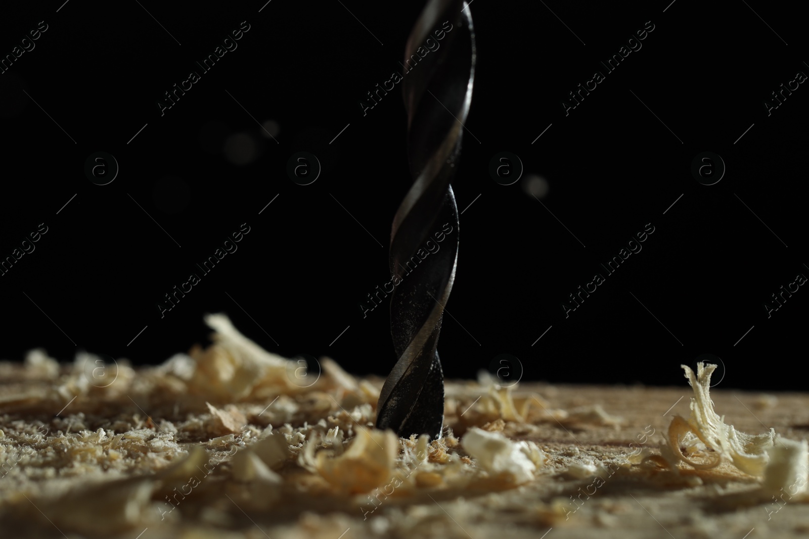 Photo of Electric drill and sawdust on black background, closeup