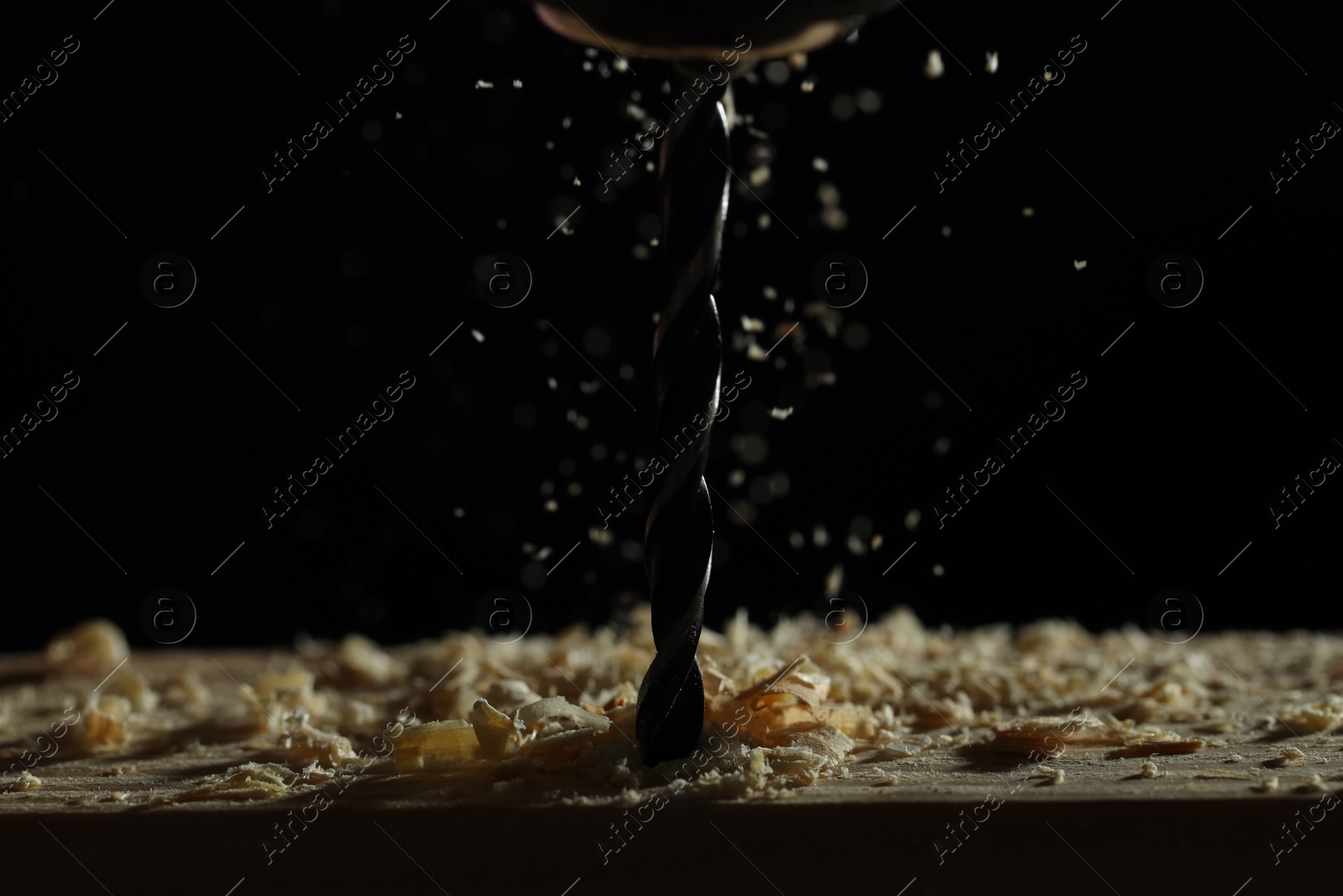 Photo of Electric drill and sawdust on black background, closeup