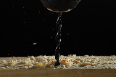 Photo of Electric drill and sawdust on black background, closeup