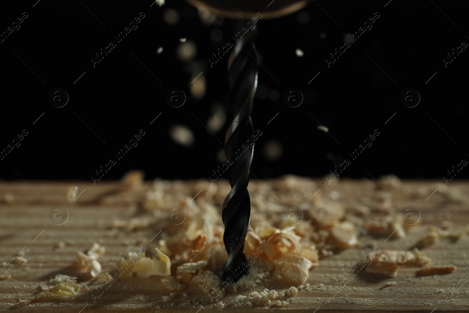Photo of Electric drill and sawdust on black background, closeup