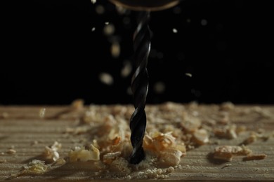 Electric drill and sawdust on black background, closeup