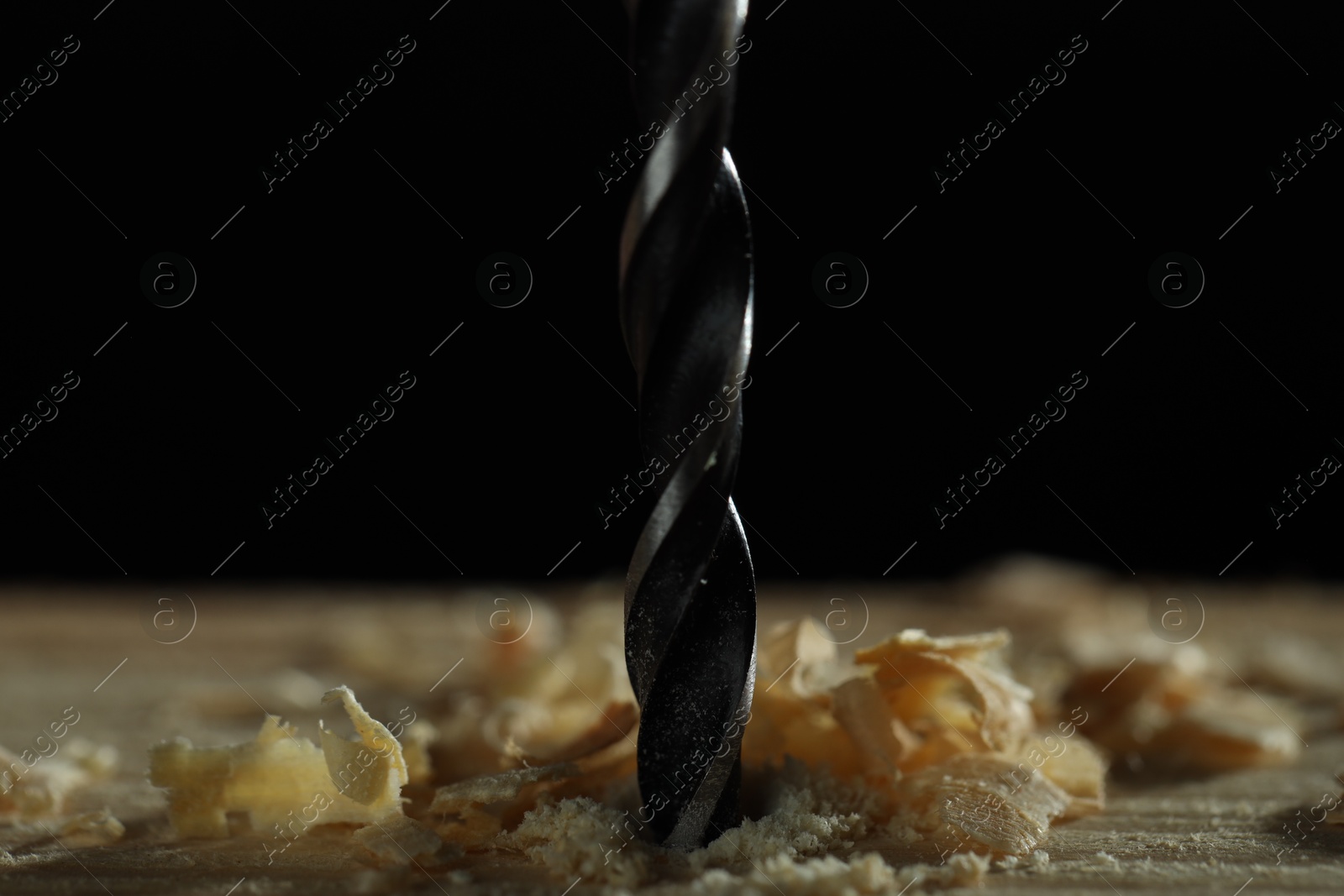 Photo of Electric drill and sawdust on black background, closeup