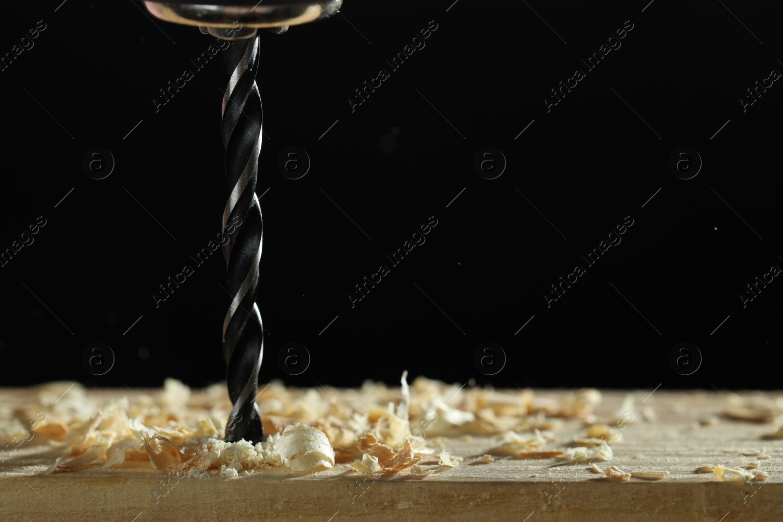 Photo of Electric drill and sawdust on black background, closeup. Space for text