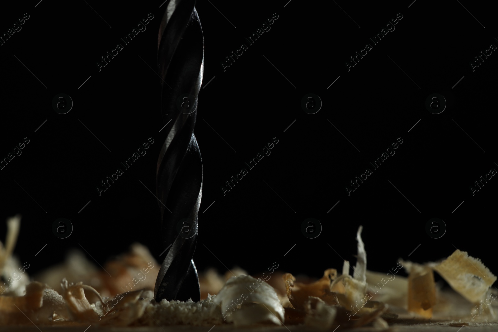 Photo of Electric drill and sawdust on black background, closeup. Space for text
