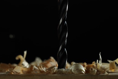Photo of Electric drill and sawdust on black background, closeup