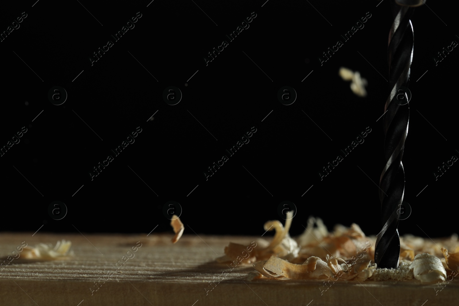 Photo of Electric drill and sawdust on black background, closeup. Space for text