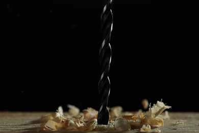 Electric drill and sawdust on black background, closeup