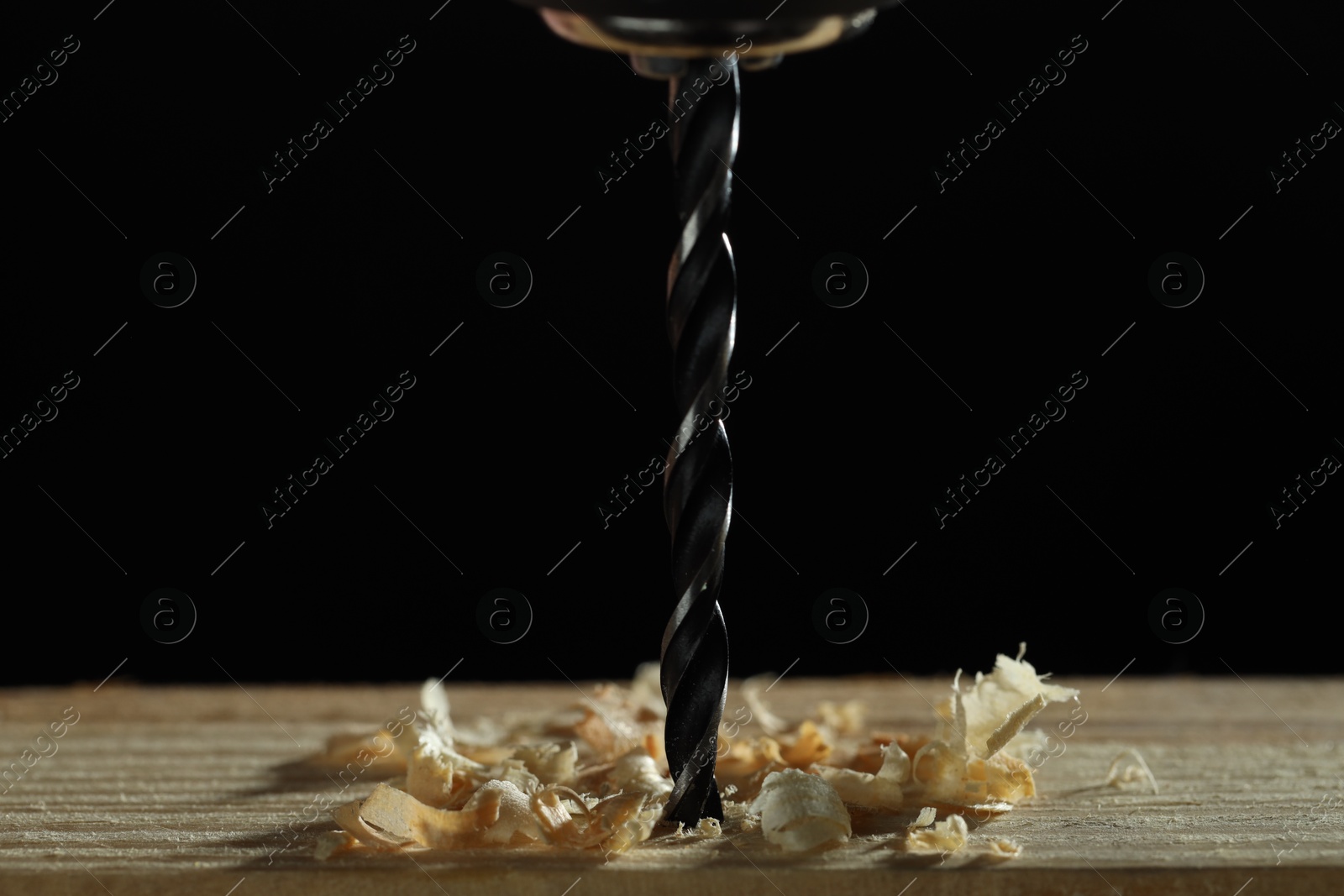 Photo of Electric drill and sawdust on black background, closeup