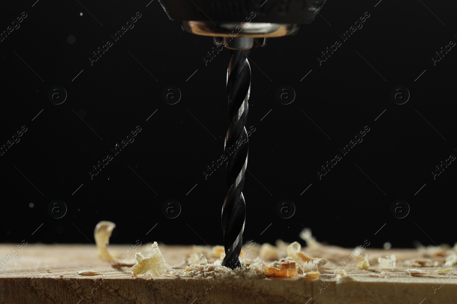 Photo of Electric drill and sawdust on black background, closeup