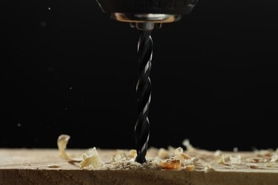 Electric drill and sawdust on black background, closeup