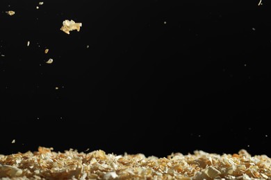 Dry natural sawdust falling on black background, space for text