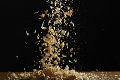 Photo of Dry natural sawdust falling on table against black background
