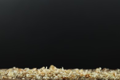 Dry natural sawdust on black background, space for text