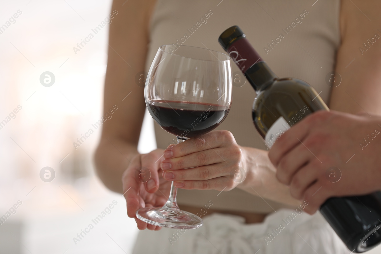 Photo of Man pouring red wine into woman`s glass indoors, closeup