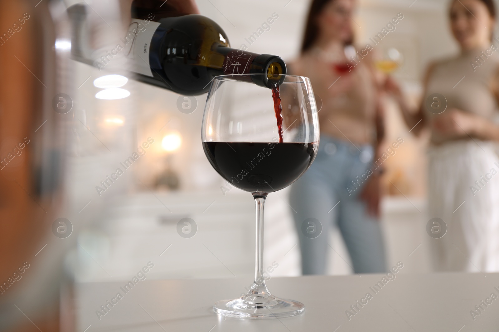 Photo of Man pouring red wine into glass at white table, selective focus