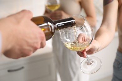 Photo of Man pouring wine into woman`s glass indoors, selective focus