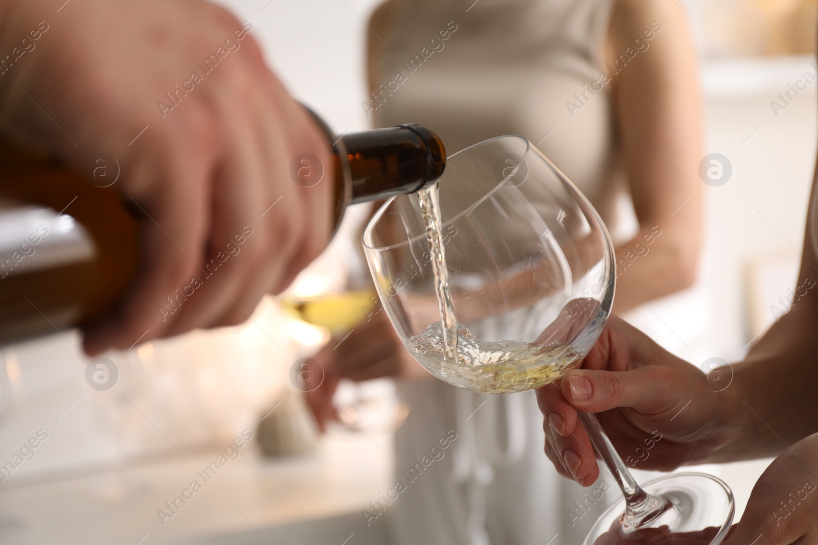 Photo of Man pouring wine into woman`s glass indoors, selective focus